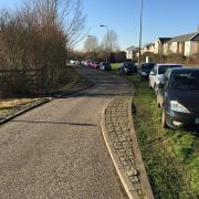Cars parked on green space in Mallards Way, Bicester.