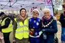 Jane Barnes, the chair of volunteer-run Amersham Action Group (L) with BJ Tailor from Tesco (C) and Mayor Cllr Elizabeth Shepherd (R) taken outside AAG's stall at the Christmas Festival last year