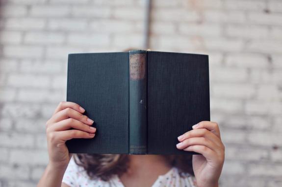 Bicester Advertiser: A woman reading with a book in front of her face. Credit: Canva Bicester Advertiser: A woman reading with a book in front of her face. Credit: Canva