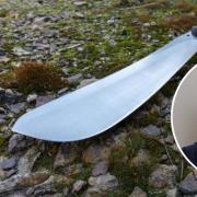 A man was injured by a machete during an assault near Banbury (stock image of 'gang' member wearing balaclava and machete)